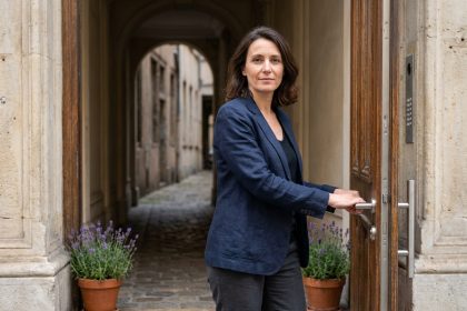 Femme examinant une serrure multipoints moderne sur une porte d'entrée en bois d'un appartement de rez-de-chaussée lyonnais